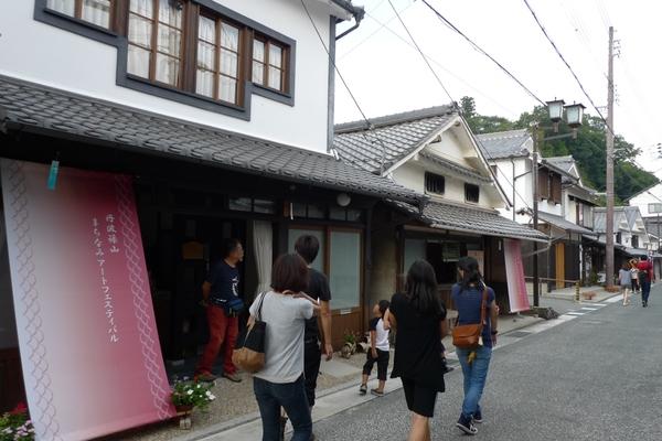 まちなみアートフェスティバルの、のれんがかかる街並みを歩いている老若男女の写真